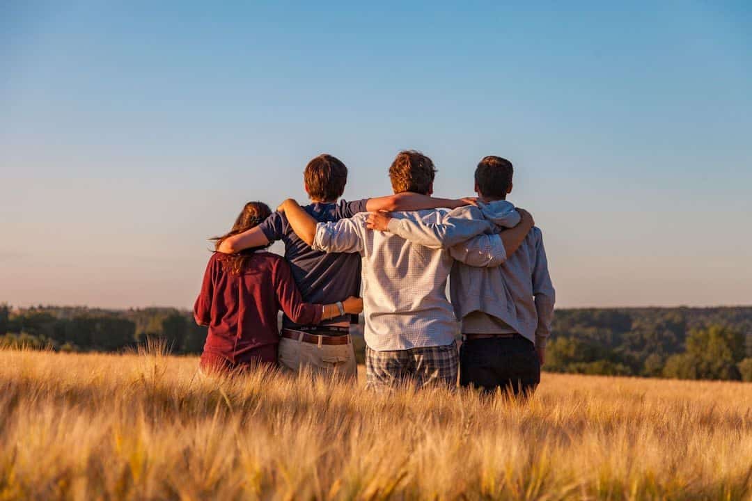 A group of friends standing in a field with arms around each other, learning how to heal psychological trauma.